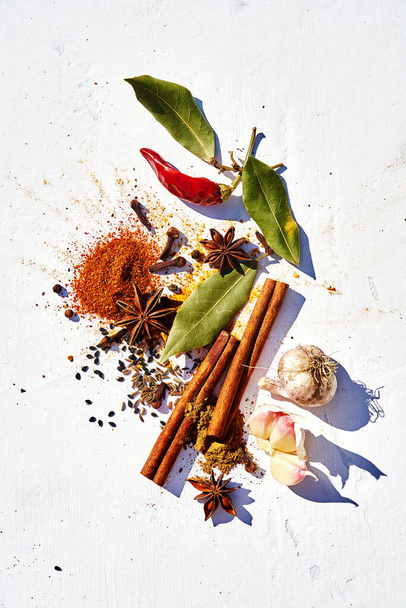 Food spices background with paprika, turmeric, star anise, sesame, red, black, white pepper, garlic, cinnamon sticks, cloves, cumin, chili, Bay leaves on white background close-up with copy space. - Foto, afbeelding