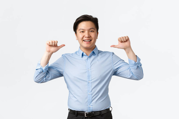 Business, finance and people concept. Proud and sassy asian male entrepreneur with teeth braces pointing at himself, show-off or bragging achievement, standing white background - Photo, Image
