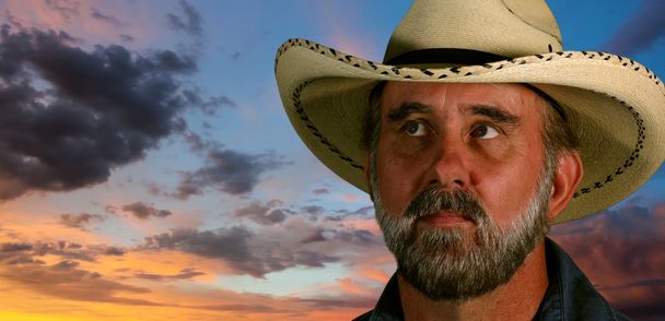 Un uomo con un cappello da cowboy bianco al tramonto
 - Foto, immagini
