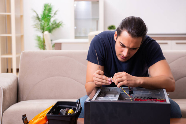 Giovane uomo che ripara computer a casa
 - Foto, immagini