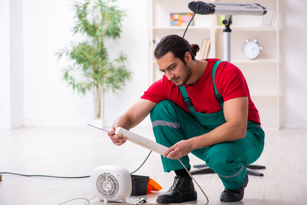 Jeune entrepreneur réparation ventilateur chauffe à l'intérieur - Photo, image