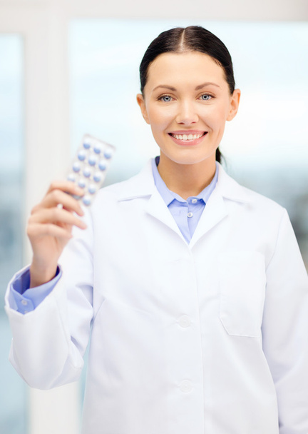 Smiling young doctor in cabinet with pills - Фото, изображение