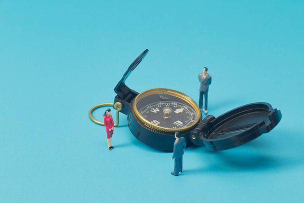 Miniature businessman and compass on bright blue backgroun - 写真・画像