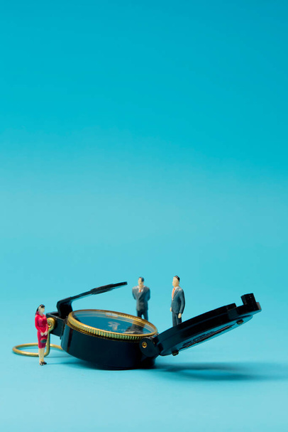 Miniatuur zakenman en kompas op helderblauwe achtergrond - Foto, afbeelding
