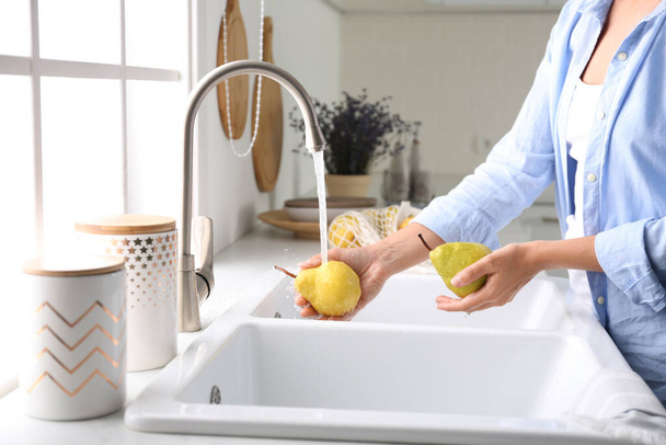 台所で新鮮な熟した梨を洗う女性,クローズアップ - 写真・画像