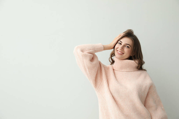 Beautiful young woman wearing warm pink sweater on light background. Space for text - 写真・画像