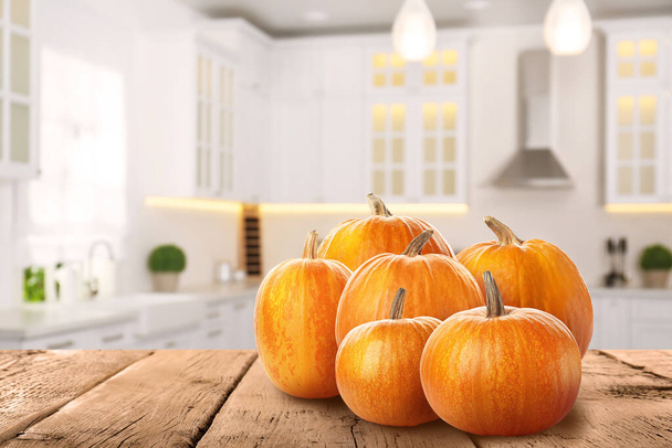 Fresh pumpkins on wooden table in kitchen. Space for text - Фото, зображення