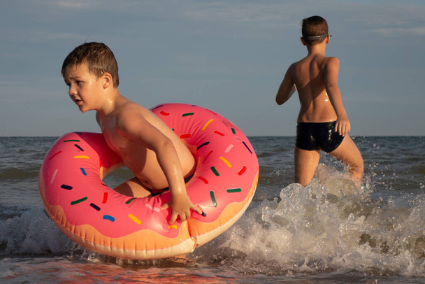 兄弟5と10歳は泳ぎ、海岸近くの海で楽しんでいます。緑色のスイミングゴーグルを身に着けています。 - 写真・画像