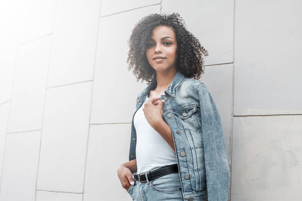 Mulatto black curly girl on street. Sunny summer city. Young woman denim style - Foto, afbeelding