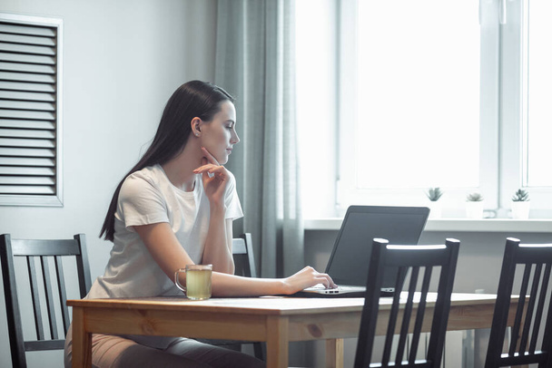 Mädchen arbeiten am Computer-Laptop im hellen Raum. Frau chattet in sozialem Netzwerk über Netzbuch in modernem Interieur - Foto, Bild