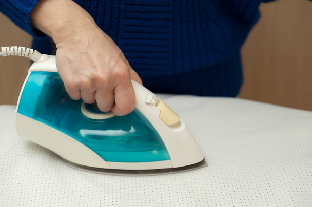 Woman ironing white clothes on ironing board. Close-up. Housework. Indoors. Horizontal shot. - Fotografie, Obrázek