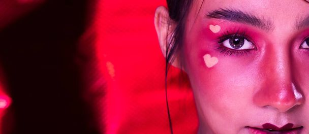 Portret van Fashion 20s Aziatische vrouw heeft mooie update make-up kunstenaar, ze past Modieuze ogen cosmetische, sexy gevoel poses over Red love Thema Toon - Foto, afbeelding