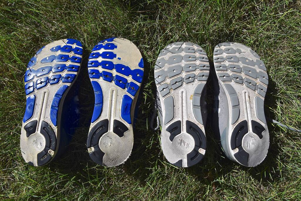 Nadměrné opotřebení na vnějších podpatcích běžeckých bot ukazuje, jak se noha nerovnoměrně dotýká povrchu.. - Fotografie, Obrázek