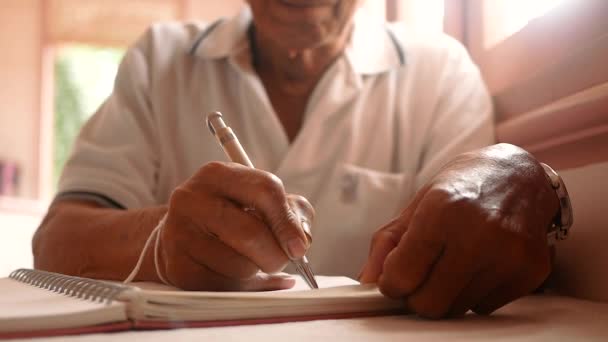 老人は一枚の紙に手紙を書いている。ノートブック上の日のためのメモを書いている古い男性の手の閉じる. - 映像、動画