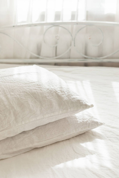 Ropa de cama textil de lino blanco. Montón de almohadas. Acogedor dormitorio interior y hermosa luz de la mañana. Color pastel. Ropa natural orgánica de moda. - Foto, imagen