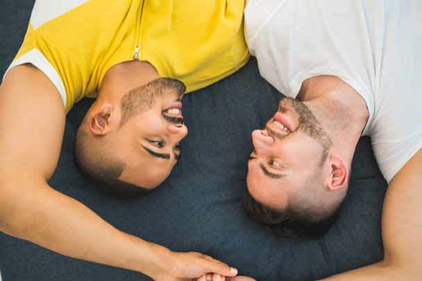 Porträt eines glücklichen homosexuellen Paares, das Zeit verbringt und sich auf den Boden legt. Lgbt und Liebeskonzept. - Foto, Bild