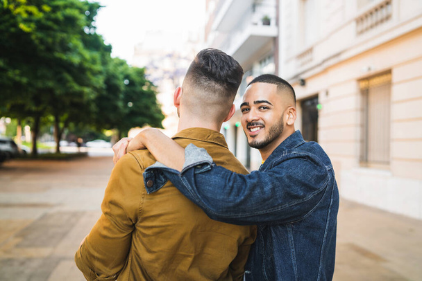 Portrait of happy gay couple spending time together and hugging in the street. Lgbt and love concept. - Фото, изображение