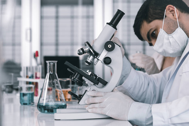 Male scientist working looking at Microscope with sample test tube in a chemistry lab scientist researcher are doing investigations in Laboratory analysis background - Φωτογραφία, εικόνα
