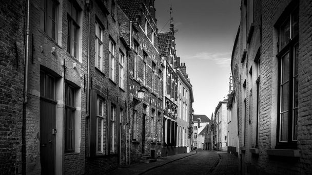 Bruggy / Belgie - 18. září 2018: Černobílá fotografie typické dlážděné ulice s cihlovými domy v historickém městě Bruggy, Belgie - Fotografie, Obrázek