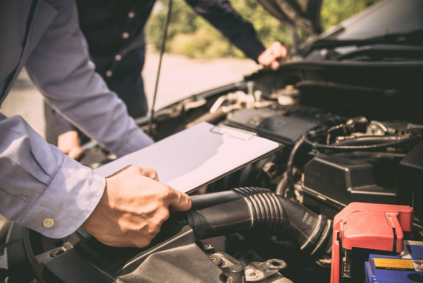 Auto mechanic using checklist for car engine systems after fixed. concepts of car insurance support and services. - Valokuva, kuva