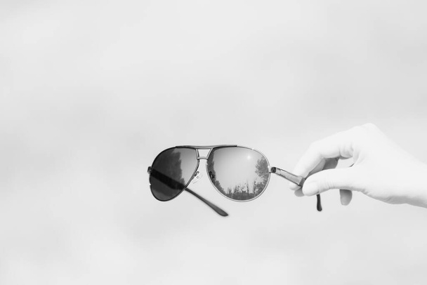 Gafas de sol retro aviator modelo agarre a mano en un primer plano de día de verano. Enfoque selectivo - Foto, imagen