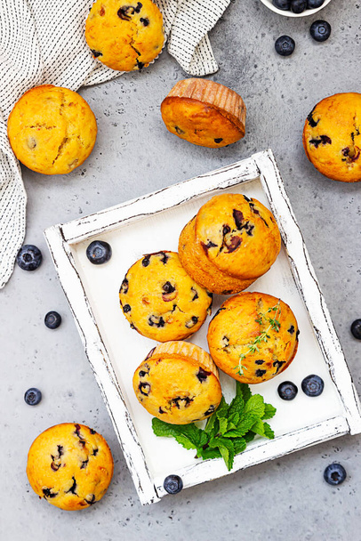 Blueberry muffins with thyme, mint and fresh berries in a wooden tray. Grey concrete background. - Zdjęcie, obraz