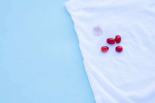 mancha de baga barberry em clothes.isolated no fundo azul - Foto, Imagem