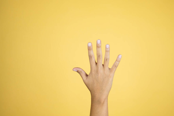 Hand over isolated yellow background showing with fingers number five - Foto, Imagem