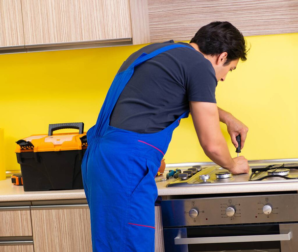 Jonge dienstverlener die keukenmeubilair monteert - Foto, afbeelding