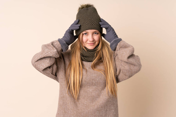Подросток украинская девушка в зимней шляпе изолированы на бежевом фоне несчастны и разочарованы чем-то. Отрицательное выражение лица - Фото, изображение