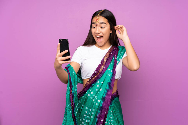 Young Indian woman with sari over isolated background making a selfie - Photo, Image