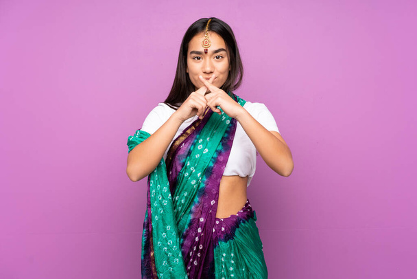 Junge Inderin mit Sari über isoliertem Hintergrund zeigt Zeichen der Stille - Foto, Bild