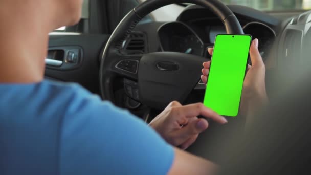 Motorista usando um smartphone dentro do carro. Smartphone Chromakey com tela verde. Navegação automática. Vício em Internet - Filmagem, Vídeo