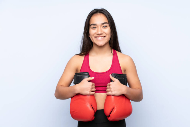 Young Indian sport woman isolated on blue background with boxing gloves - Photo, Image