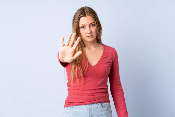 Teenager Ukrainian girl isolated on blue background making stop gesture - Foto, Bild