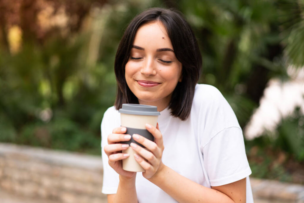 Junge hübsche Frau hält Kaffee zum Mitnehmen im Freien - Foto, Bild