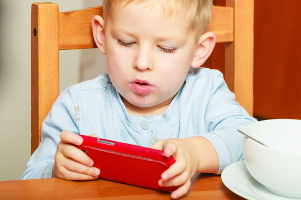 boy kid child eating corn flakes breakfast playing mobile phone - Foto, Imagem
