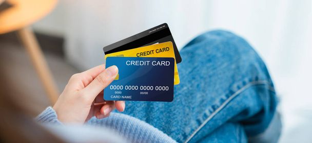 Female hand holding credit cards on the sofa. - Zdjęcie, obraz