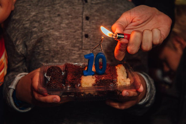 Крупный план человека, зажигающего свечи на куске торта - Фото, изображение