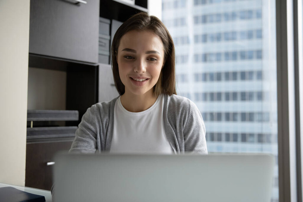 Smiling young businesswoman employee looking at laptop screen, working online - Zdjęcie, obraz