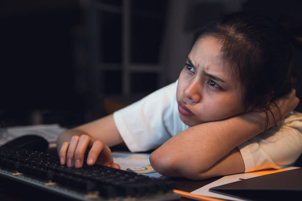 Стрессовая азиатская деловая женщина сидит на стуле и смотрит на экран компьютера в офисе ночью. - Фото, изображение