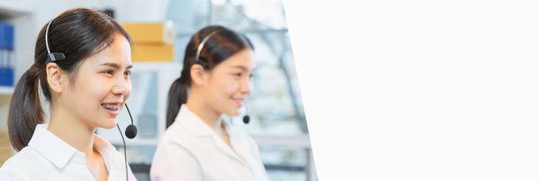 Lächelnde asiatische Unternehmensberaterin mit Mikrofon-Headset des Kundendiensttelefonisten am Arbeitsplatz. - Foto, Bild