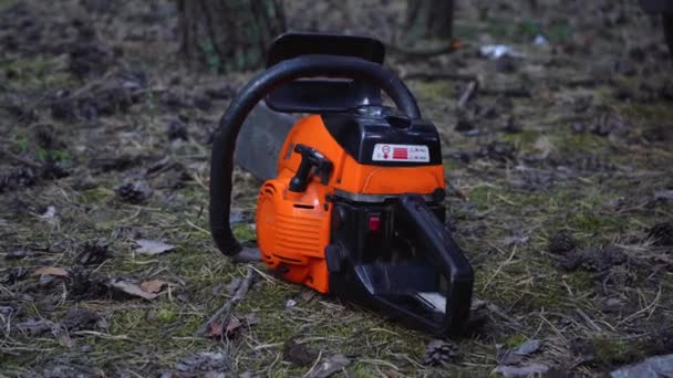 narancs láncfűrész fekszik a földön az erdőben - Felvétel, videó