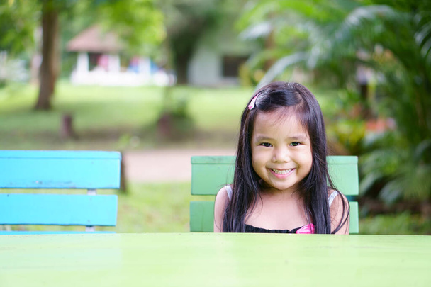 Азиатские дети или девочка ребенок и студент, думая о новой идее и веселое веселье или расслабиться улыбка на красочный стол со стулом и сад природы в детском саду или детском саду и летние каникулы путешествия - Фото, изображение