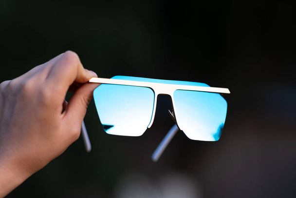 Las gafas de sol sobredimensionadas sostienen a mano el primer plano. Enfoque selectivo - Foto, imagen