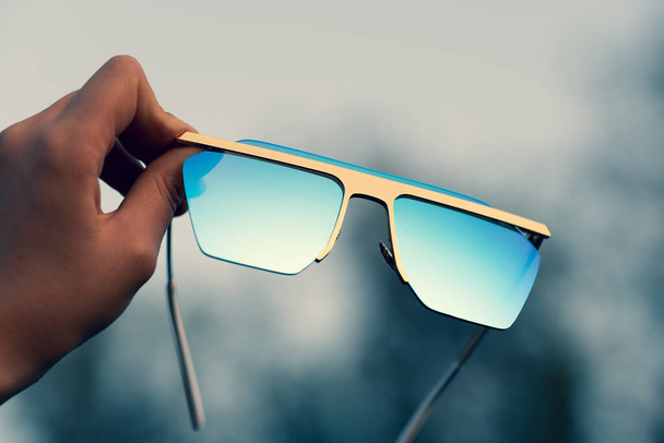 Oversized sunglasses hold by hand closeup. Selective focus - Foto, imagen