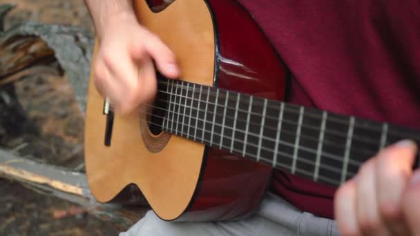 ένας άντρας παίζει κιθάρα ενώ κάθεται στο δρόμο - Πλάνα, βίντεο