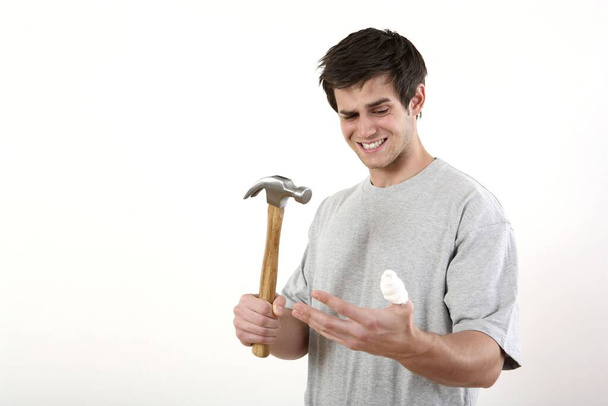 Man with hammer looking at his injured thumb - Фото, изображение