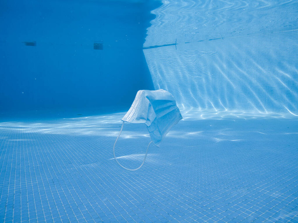 A closeup shot of a protective face mask drowned in the water of a pool - Foto, Imagen