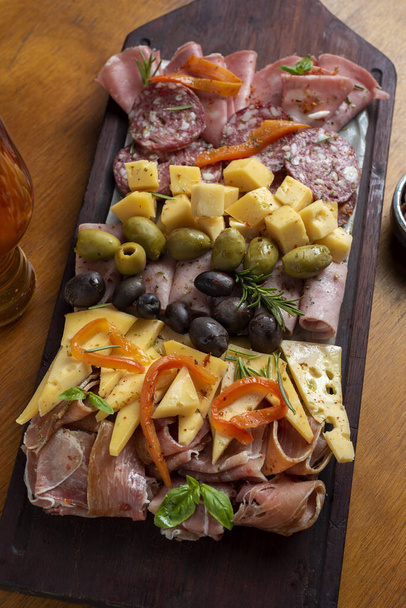 A Vertical shot of delicious dairy and meat food on a wooden plate served with beer - Foto, afbeelding